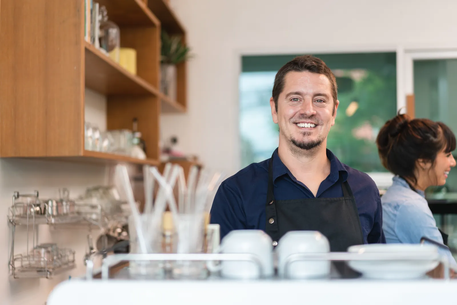 A café owner smiling behind the counter of his coffee shop